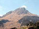 Volcano with smoking rocky top and lower parts without vegetation.