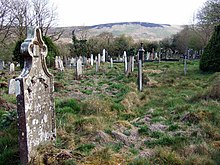 rough grass burial ground with old gravestones and a mountain in the distance