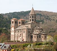 Saint-Nectaire, en Puy-de-Dôme con una torre de crucero poligonal como Cluny, contrafuertes planos y un alto ábside oriental con bajos absidiolos radiantes que forman una cabecera.