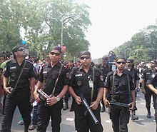 Armed men in black uniforms on a street