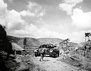 A tank drives up a rocky ridge