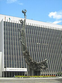 Picture of the monument, a crescent-like stone artwork covered with several bronze statues.