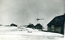 Photo noir et blanc d'un avion volant très bas dans un paysage enneigé.