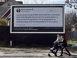 A billboard shows a paragraph of text by Boris Johnson, presented as a tweet. A woman and a girl, pushing a baby-buggy walk past, looking straight ahead.