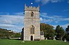 Square stone tower surrounded by trees and grass.