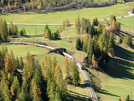 Southbound train after leaving God loop tunnel (view from footpath to Piz Darlux) Südwärts fahrender Zug nach dem Verlassen des God Kehrtunnels (Blick vom Fussweg zum Piz Darlux)