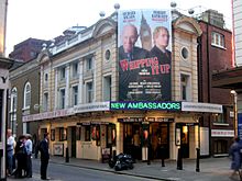 Exterior view of theatre with large poster advertising the current attraction.