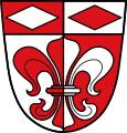 Gemeinde Leitershofen Unter einem von Rot und Silber gespaltenen Schildhaupt, darin zwei liegende Wecken in verwechselten Farben, gespalten von Silber und Rot mit einer heraldischen Lilie in verwechselten Farben.