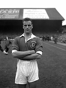 A footballer poses for a photo in front of a stand