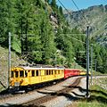 Een historische RhB ABe 4/4 I maakt een toeristische tocht over de Berninabahn. Achteraan zijn open rijtuigen te zien.