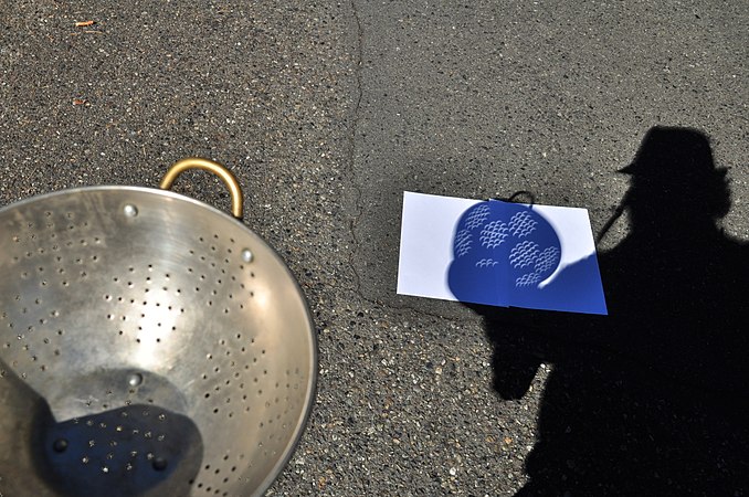 Shadow of a photographer, holding a colander to photograph the projection of solar eclipse in August 2017