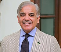 Man in his seventies wearing a great jacket, blue shirt and dark tie