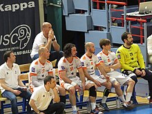 Handballeurs assis sur leur banc de touche.