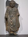 Buddha Gautama debout vêtu d'une robe monastique[N 7]. Région du Gandhara, Ier – IIIe siècle schiste, Musée Guimet