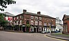 A brick public house in three storeys with some rendering on the ground floor