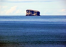 Petite île rocheuse aux falaises abruptes isolée au milieu de l'océan.