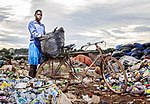 En ung man i Uganda plockar sopor på en soptipp. På grund av platsen och förhållandena finns en hög risk att bli sjuk eller skadad om man tvingas plocka skräp på det här viset.