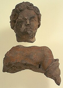Statuette dite de Jupiter, fragmentaire (une partie pour le buste, une pour la tête). Couleur ocre. Les cheveux du personnage sont bouclés.