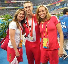 Photo de 3 gymnastes canadiens, deux femmes sur les côtés et un homme en tenue au centre