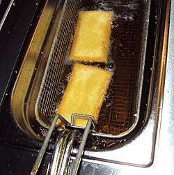 Dua pastri diturunkan dalam bakul ke dalam minyak