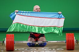Złoty medalista i rekordzista olimpijski Ruslan Nurudinov prezentuje flagę Uzbekistanu