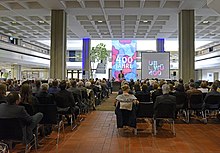 Mit Menschen gefüllte Halle der Zentralbibliothek am Festakt der Universitätsbibliothek Würzburg