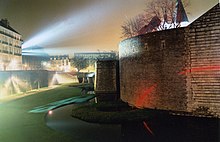 Photographie du château éclairé la nuit.