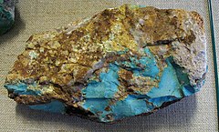 A rough nodule of turquoise in brown matrix with a split face showing areas of intense turquoise blue.