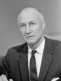 Thurmond sitting in a suit and tie holding a pen