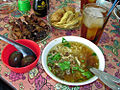Una selezione di cucina indonesiana, incluso Soto Ayam (zuppa di pollo), sate kerang (saté), telor pindang (uova), perkedel (fritto) e il es teh manis (tè dolce ghiacciato)