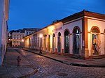 A cobblestone street of old single-storied brightly colored houses