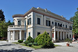 Vue d'une villa blanche, avec des colonnes sur une partie de sa façade.