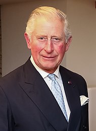 Porträttfoto av Prins Charles, i mörk kavaj, vit skjorta, ljusblå slips.