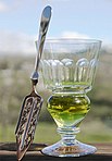 Reservoirglas mit natürlich gefärbtem Absinth und Absinthlöffel