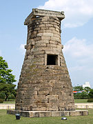 Photographie d'un monument en pierre en extérieur. De forme allongée se rétrécissant à son sommet, une unique ouverture de fome carrée est visible à mi-hauteur.