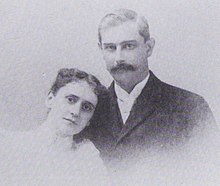 A black-and-white photographic portrait of a man and woman from the shoulders up