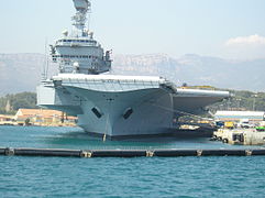 Le Charles de Gaulle à quai à Toulon avec le Baou de Quatre Ouro en arrière-plan.