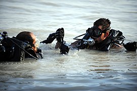 US Navy 091116-N-4154B-105 Navy Diver 2nd Class Zachery Dojaquez and an Iraqi Navy diver work together to run lifting wires from a crane to a sunken barge during dive operations.jpg