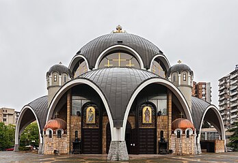 Vista frontal da igreja de São Clemente de Ocrida, Escópia, capital da República da Macedônia. Esta igreja ortodoxa foi projetada por Slavko Brezovski e consagrada em 1990, depois de 18 anos de construção. A igreja, de tipo rotunda, é composta unicamente de cúpulas e arcos. É um dos exemplos recentes mais destacados da arquitetura macedônica e a maior catedral entre as ortodoxas macedônicas. (definição 4 450 × 3 057)