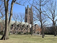 Picture from a distance of Green Hall - trees in foreground, bell tower included, blue skies and sun