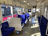 The interior of a train carriage with blue fabric seats and large windows