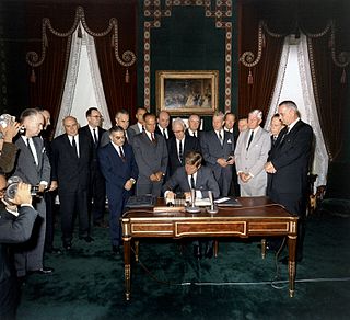 President Kennedy signing the 1963 Limited Nuclear Test Ban Treaty, one of the first arms control agreements between the West and the Soviet bloc, which ended atmospheric nuclear testing.