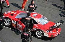 Overhead view of a racecar surrounded by personnel.