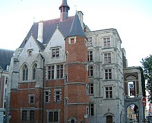 Vue de trois-quart de la façade d'un palais dont une partie est en brique rouge