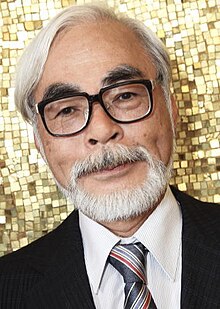 Visage d'un homme asiatique aux cheveux et à la barbe blanche en costume noir et cravate bleue avec rayures.