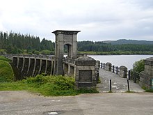 A dam head and tower, with a lake surrounded by trees