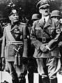 Benito Mussolini and Adolf Hitler stand together on an reviewing stand during an official visit to occupied Yugoslavia