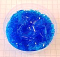 Cristales de CuSO4 pentahidratado creados artificialmente en un vaso plástico.