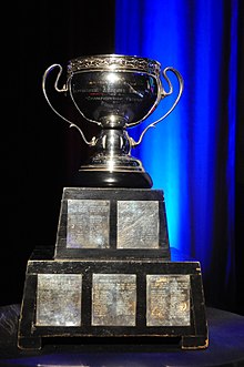 Ornate silver bowl mounted on a two-tier black wooden plinth