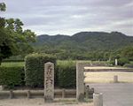 Modern stele in front of a park-like area.